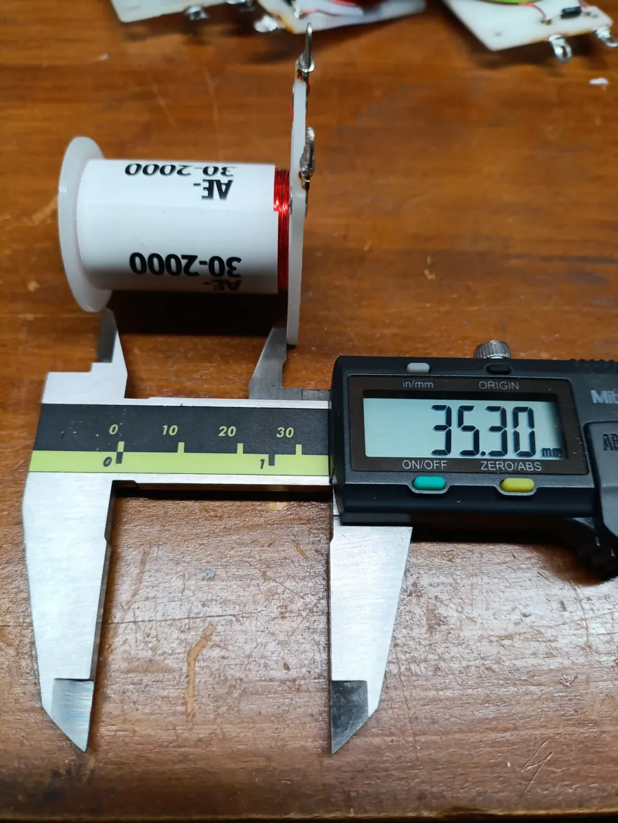 A Mitutoyo digital caliper reading 35.30 millimetres between the flanges of an AE-30-2000 coil bobbin.