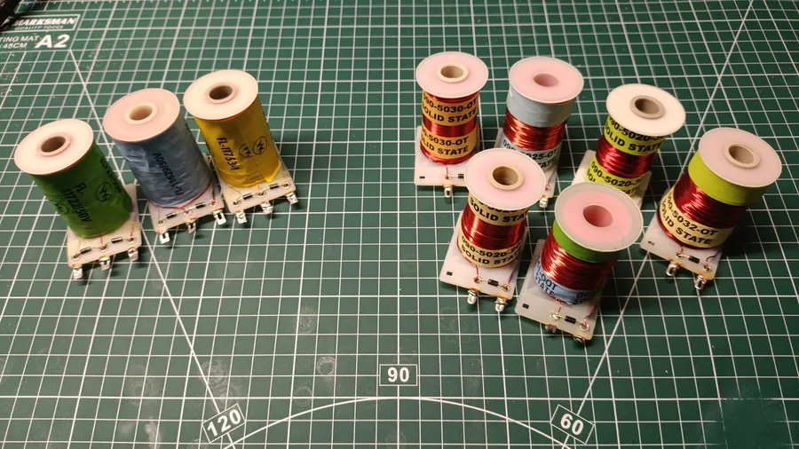 Williams dual-wound flipper coils (left group, three solder lugs visible at the base) and Data East single-wound coils (right group, two solder lugs), all fitted with flyback diodes, arranged on a green cutting mat.