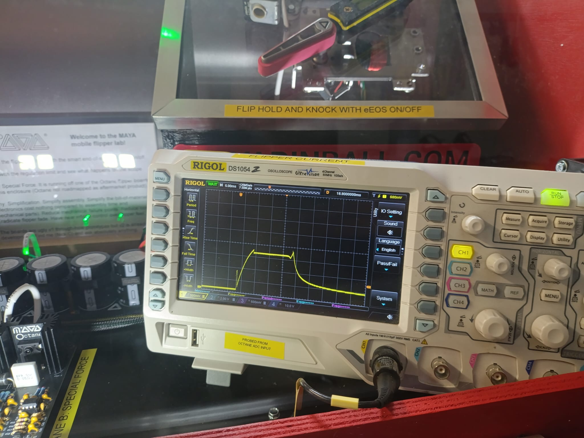 Display cabinet containing cutting-edge pinball flipper control electronics and an oscilloscope monitoring current through the coil