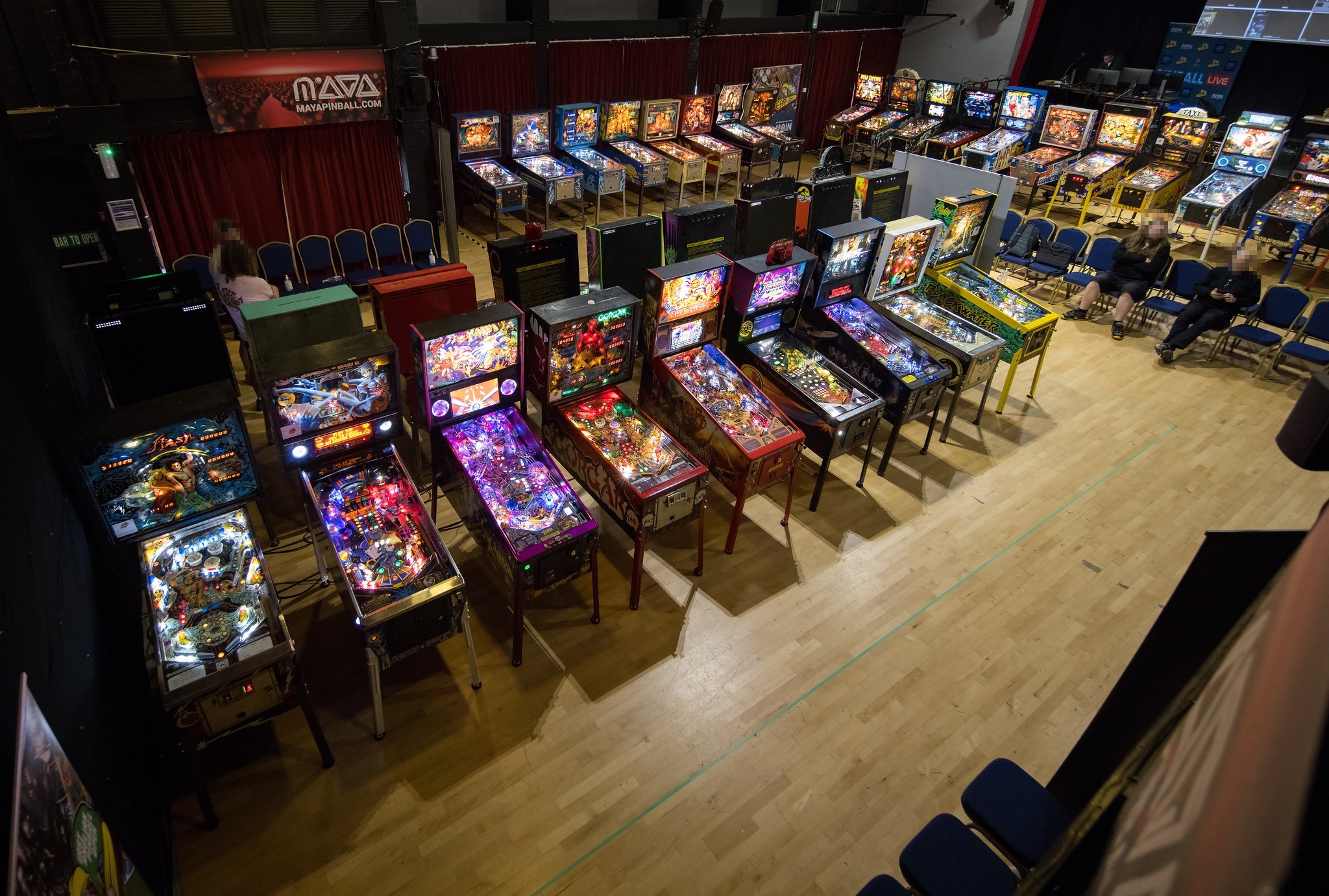 Overhead view of the EAPO 2026 tournament floor at The Carnegie, Thetford, rows of lit pinball machines with the MAYA banner visible at the rear
