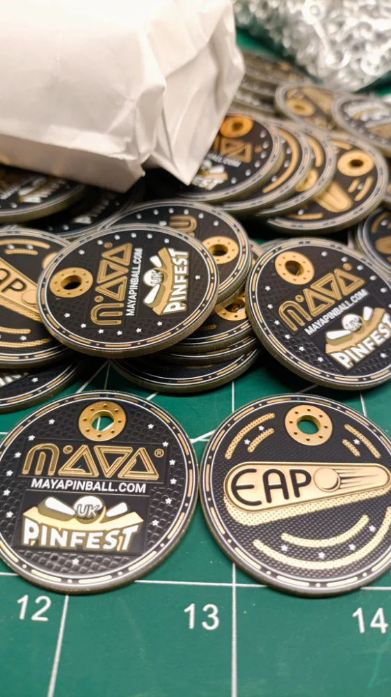 A pile of gold-plated PCB poker chips clearcoated and printed with the MAYA Pinball, UK Pinfest, and EAPO logos, made for the Bounty Strikes tournament