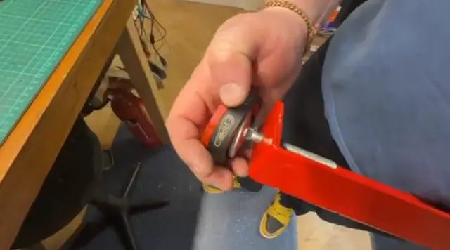 Close-up of a hand installing Pinsoles onto a pinball machine leg leveller